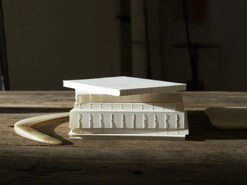 Détail illustré de tranches de papier et de reliures cousues sur un établi