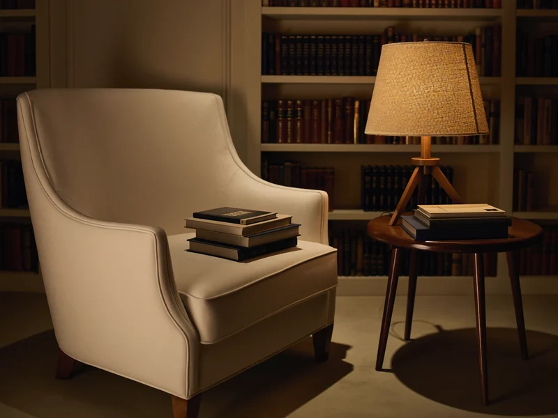 Coin lecture illustré avec fauteuil, lampe chaude et pile de livres